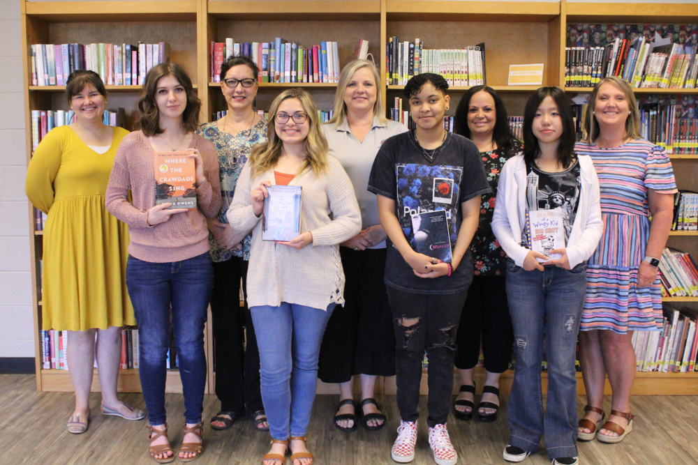 A group stands together holding library books