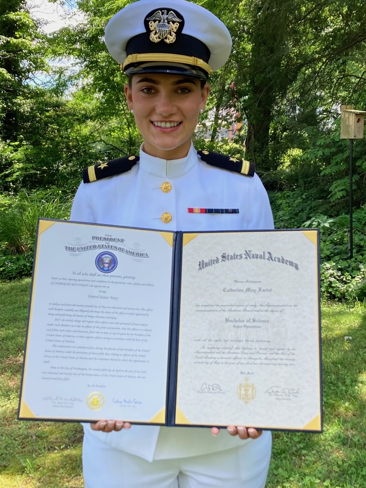 woman stands with her certificate of graduation from US Naval Academy