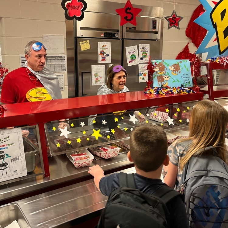 adults serving breakfast to students in the cafeteria