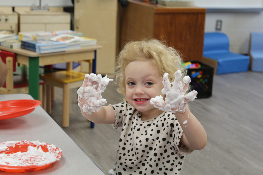 A toddler with shaving cream covered hands