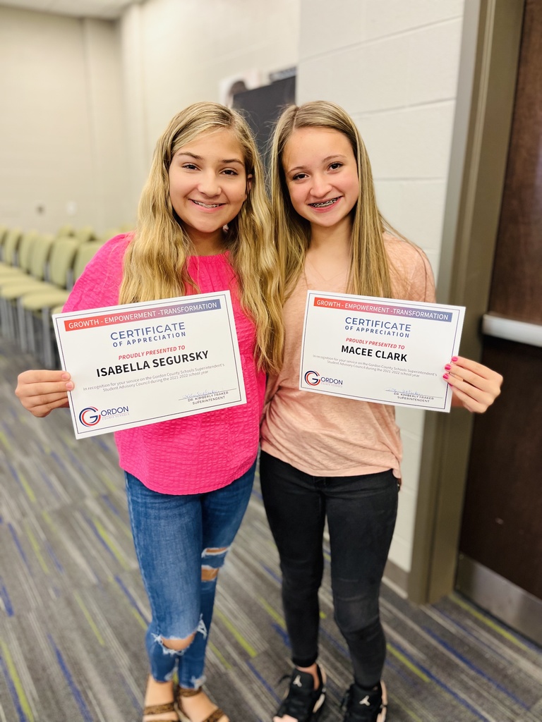 2 students stand with certificates