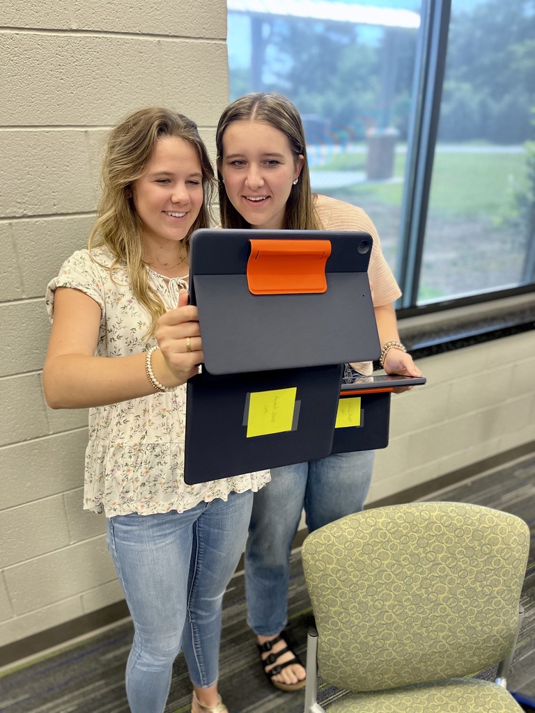 2 students stand with an ipad