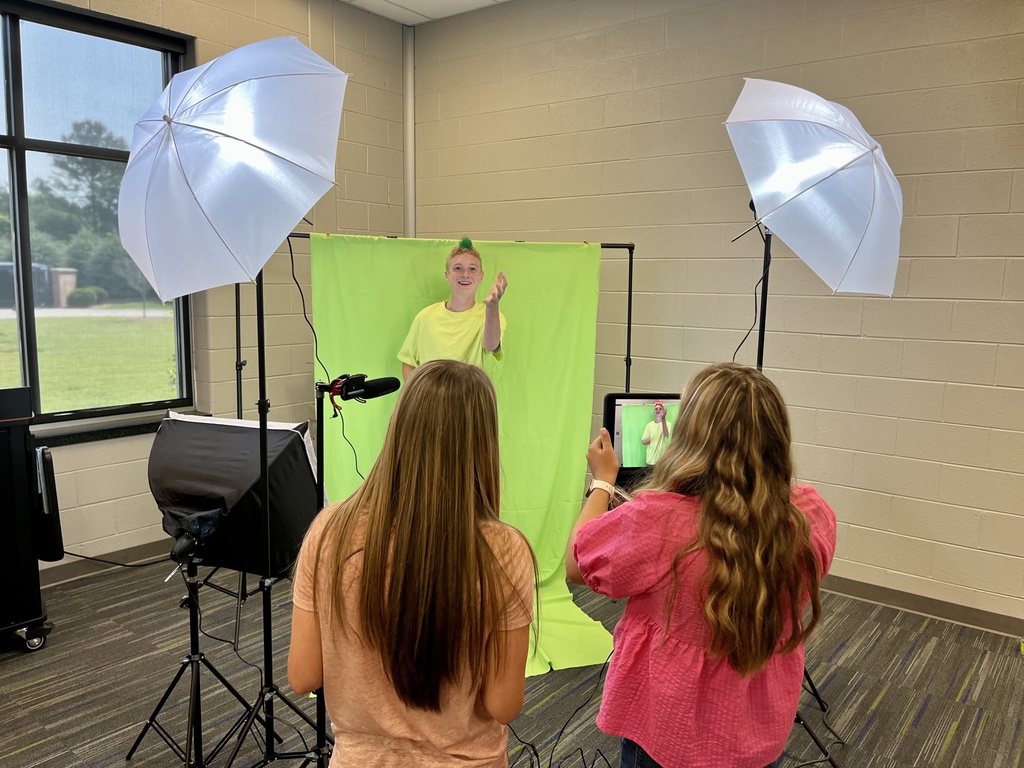 3 students filming in front of a green screen
