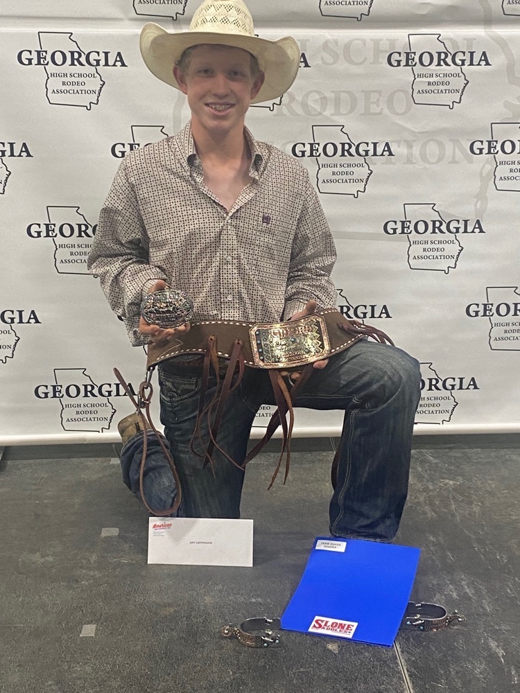 boy holds his gold buckle and other awards