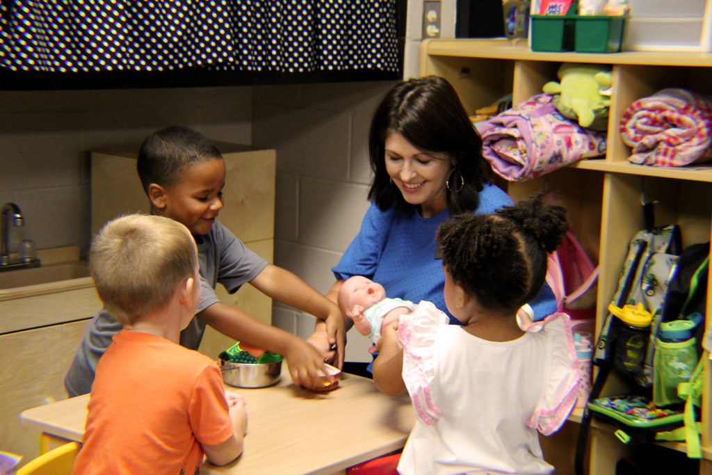 A group of students play at a table with Monica Holt