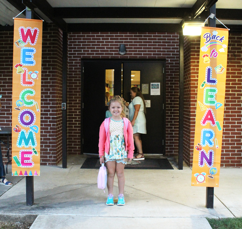 Lily Waters stands outside of the Welcome Back to Learning Sign 