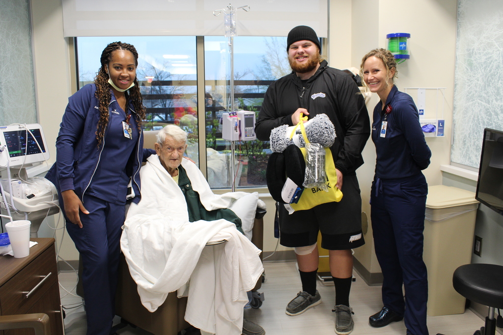 A student presents a gift bag to a cancer patient