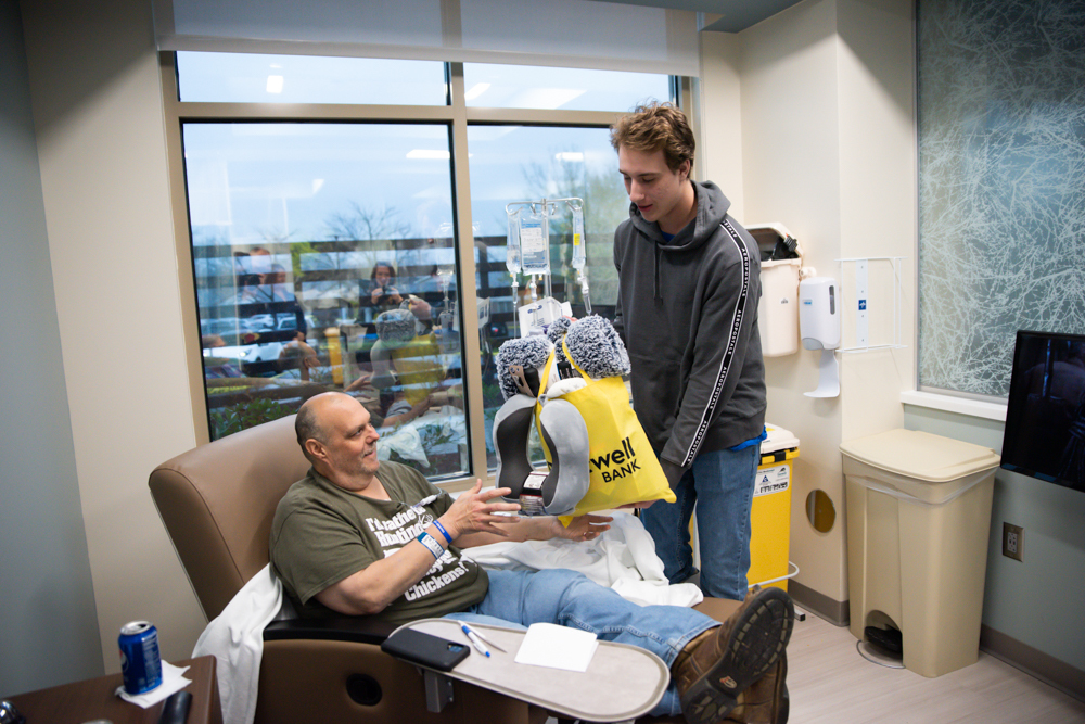 A student presents a gift bag to a cancer patient