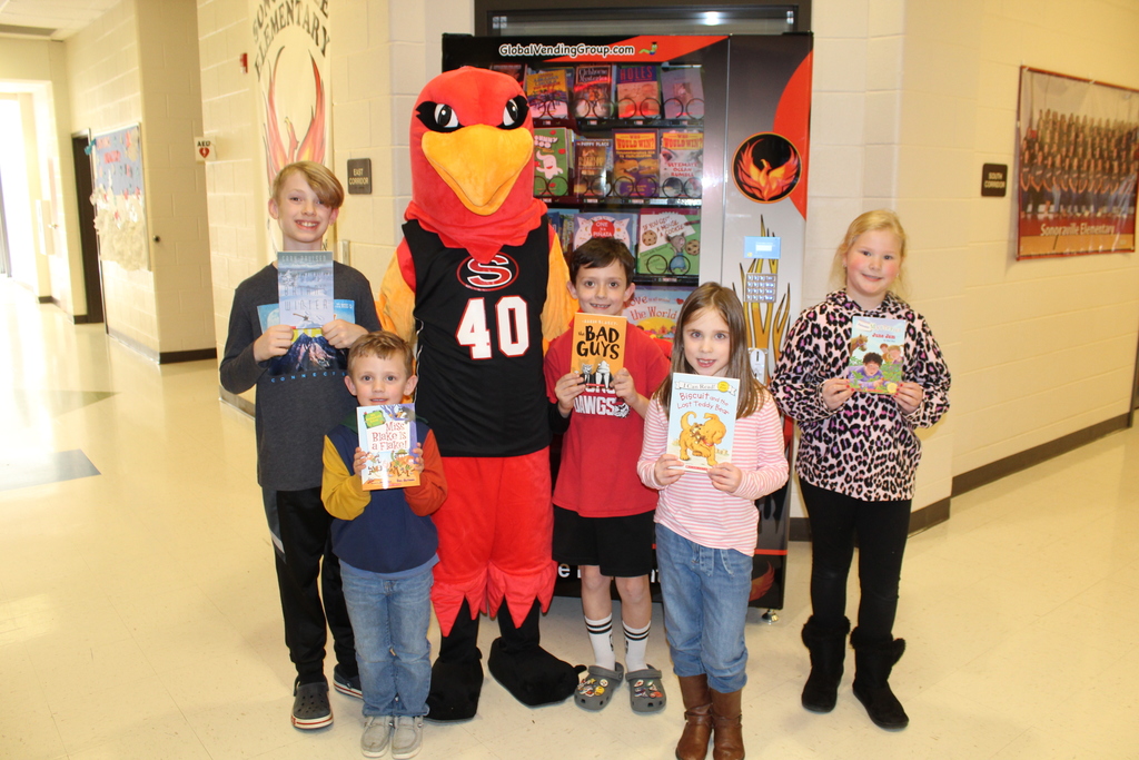 students posing with books and red bird mascot