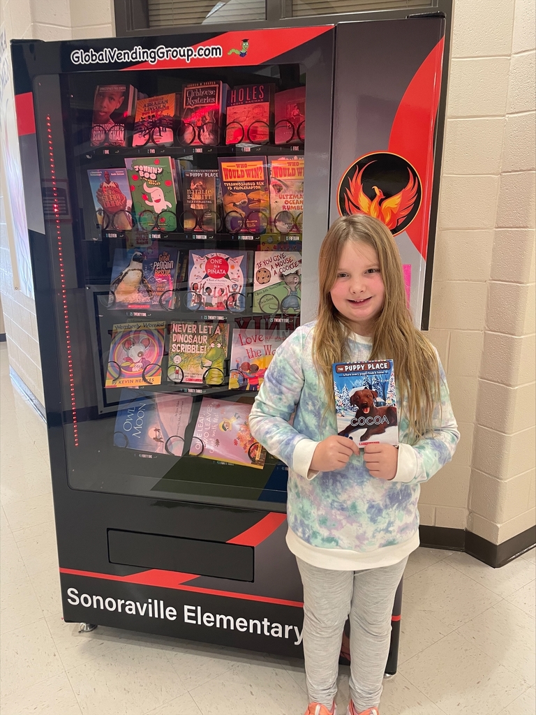 student posing with book and vending machine