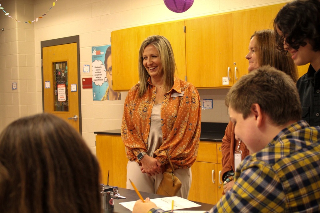 an adult smiles while surrounded by others